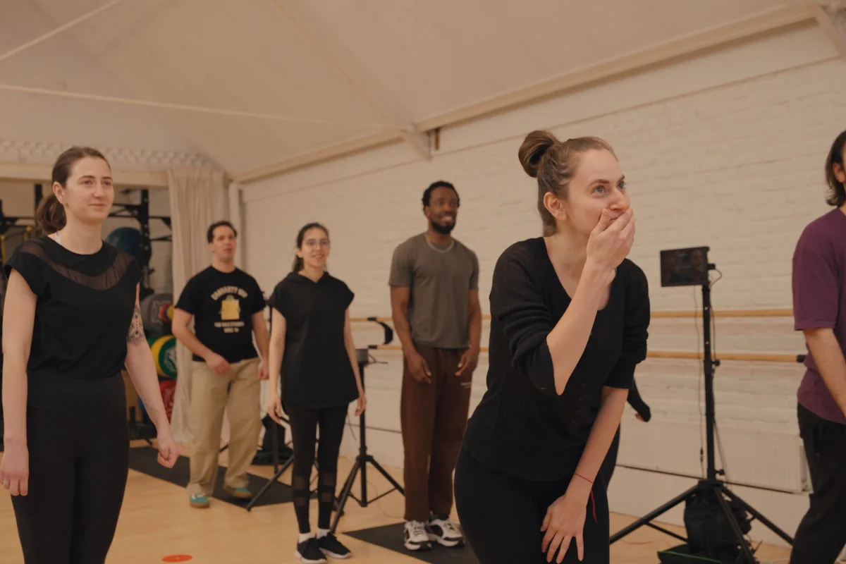 Participants stand together in the studio; one laughs with her hand over her mouth.